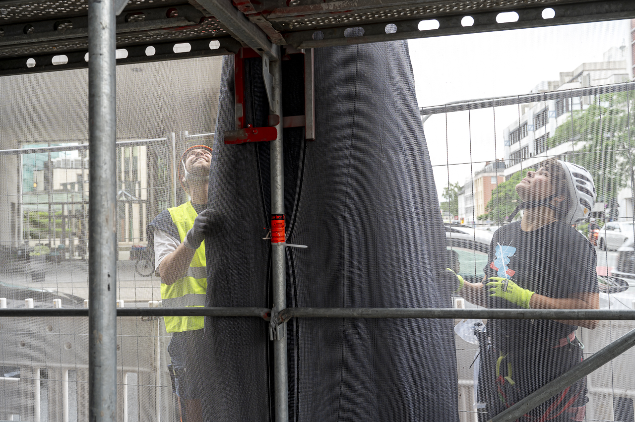 Jona Wentzler (left) and Hannah Horn (right), members of the
              construction team, mounting the fabric on the building.